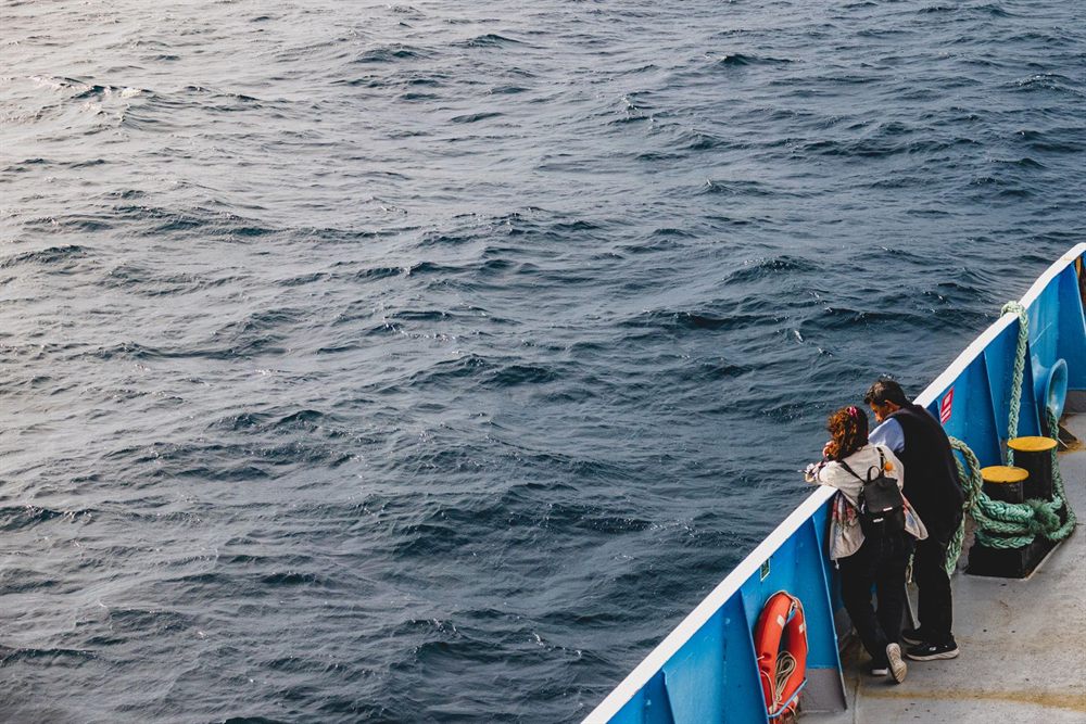 Couple leaning on a ship railing looking out over the open sea
