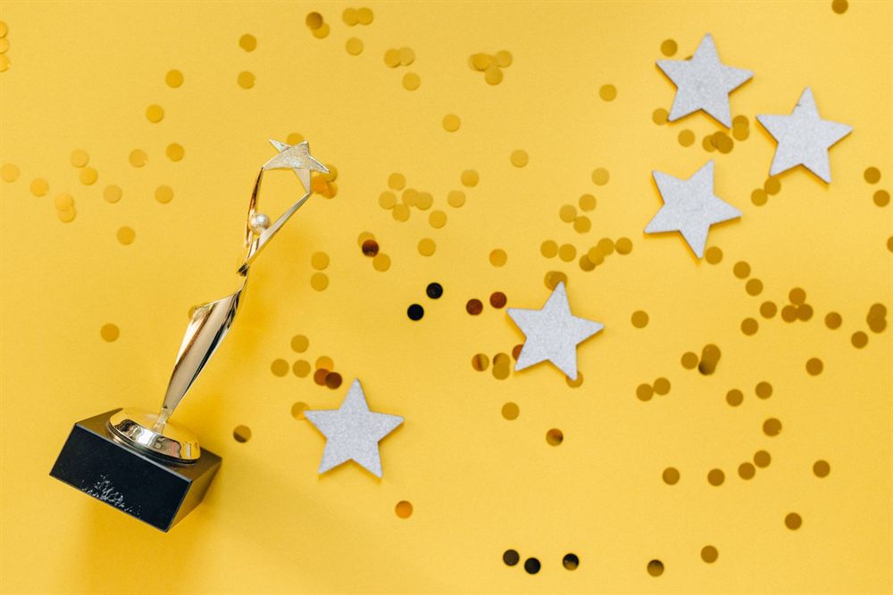 Gold star trophy and silver stars on a bright yellow background