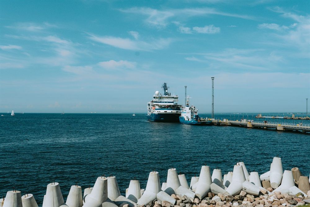 Small expedition cruise ship moored at a harbor pier behind a breakwater